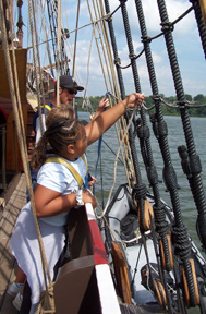 Madena clips her safety harness into the rigging as Mr. Dawson observes.