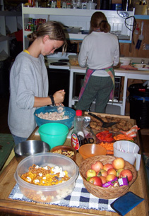 Ciara and Mrs. Lawler prepare lunch around a table laden with food.