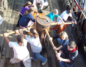 Eight members of the student crew turn the capstan.
