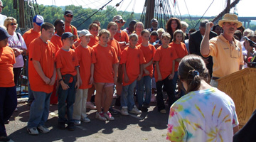 Captain Reynolds, at the podium, addresses the crew gathered behind him.