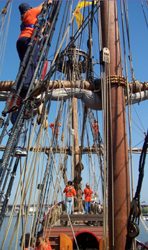 Orange-clad crew members climb the rigging to greet Albany.
