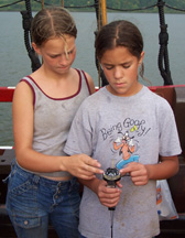 Ciara and Shannon help each other practice with a hand-bearing compass.