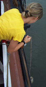 Ciara lowers a canvas bucket to the river's surface to collect a water sample for study.