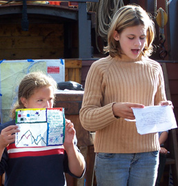 Meaghan delivers her report while Ericka holds up a graph.