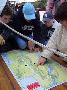 Mrs. Franz shows Sam, Alex W., and Nick their position on a modern river chart. 