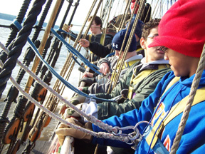 A row of students practice clipping their safety harnesses into the shrouds.