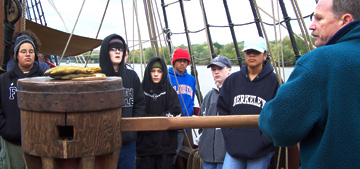 Captain Reynolds shows the new crew how to fit a bar into the capstan.