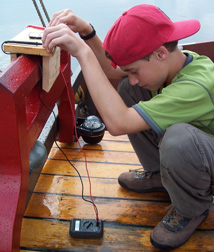 Adam uses a voltometer to measure a photovoltaic cell's output on the Quarter deck.