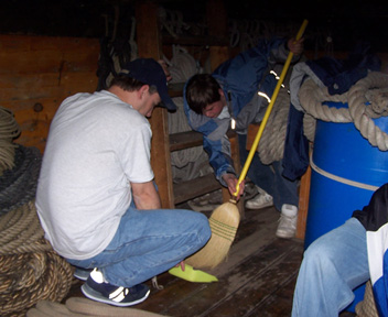 Daymien and Mr. McDonald sweep the orlop deck.