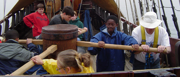Mr. Weisse and a team of students turn the capstan on the weather deck.