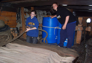 Emily and Veronica flake the anchor line on the orlop deck.