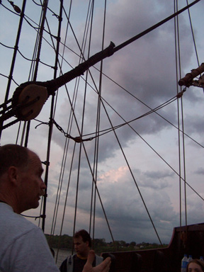 A squall front blows over the ship at sunset.