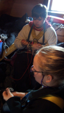Daymien and Andi make bracelets in the great cabin.