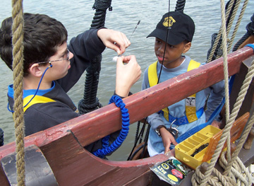 Dylan and Jamal bait a hook while fishing on the channel.