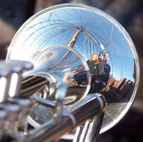 Andi, Captain Washington, and Dylan's reflections appear distorted on Mr. Weisse's trumpet.