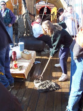 Andi mops up spilled milk on the weather deck.