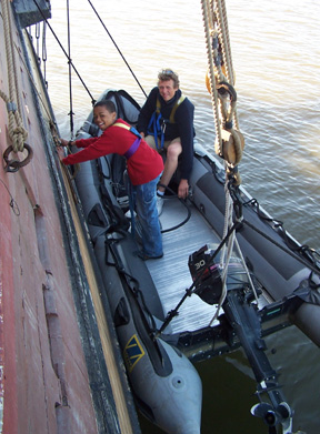 Just a few feet above the waterline, Jamal uses his foot to pump air into our inflatable boat while Mr. Berg holds the nozzle in place.