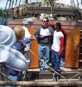 Mr. Linehan presents Jamar and several other students with an avian field guide outside the forecastle.