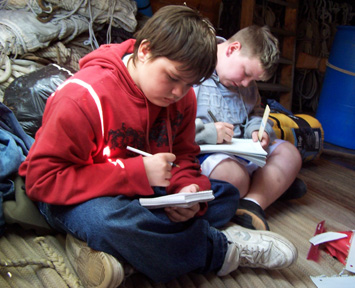 Daymien and Bryan sit on the anchor line while poring over their notes.