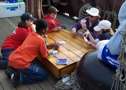 Mr. Weisse leads Jamar, Veronica, Daymien, Emily, and Bryan through a card game.