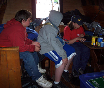 Daymien, Bryan, and Veronica check out this website on a laptop while sitting in the great cabin.