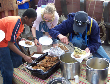 Jamar, Andi, and Mr. Dawson serve themselves dinner on the weather deck.