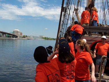 Students look on as the Half Moon approaches Albany, with a water cannons visible in the background.