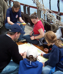 Several students pore over a river chart on the weather deck.