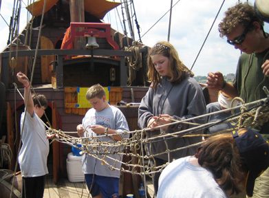 Daymien, Bryan, Ginny, and Veronica help Captain Berg make a hammock from scrap rope.