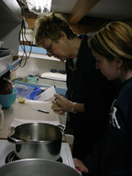 Kiera and Mrs. Barton examine a recipe in the galley.