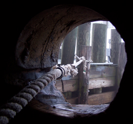 A view from the hawse hole of a mooring line running out to a foggy dock.