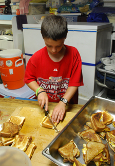 Jamie slices grilled cheese sandwiches in the galley.