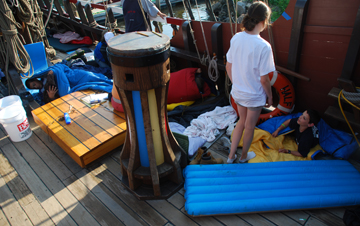 Nora rouses Jamie from his sleeping bag on the weather deck.