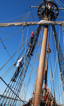 Students climb aloft on the main mast shrouds.