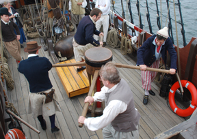 Reenactor crew members walk the capstan.