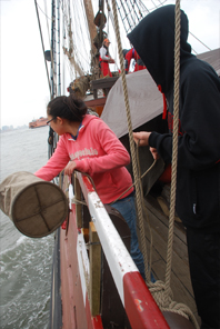 Thwe-Thwe tosses a tethered bucket overboard to collect river water.
