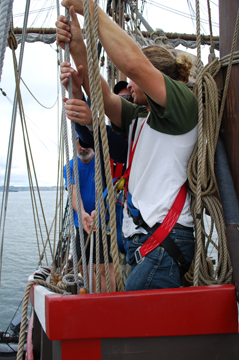 Mr. Van Grondelle and Mr. Collens sweat the anchor tackle while Mr. Mclaghlan tails.