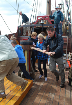 The crew walks the capstan to weigh anchor.