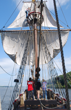 The fore mast team clews up the fore course.