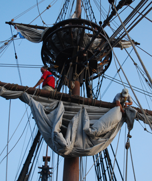 Captain Reynolds and Glen furl the main course.