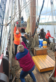 The crew sets the main top sail.