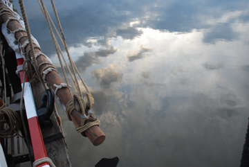 A cloudy sky reflected in the Hudson's waters off the Half Moon's beak.