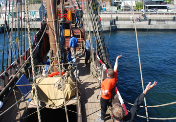 Crew members wave to shore as the Half Moon pulls away from the Customs House Pier.