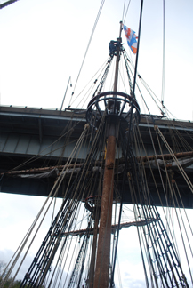 The fore mast narrowly passes under a bridge.