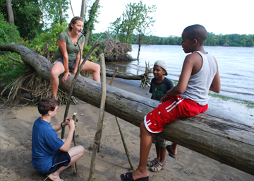 Abby and Tahari balance on a log while Jack and Jason hang out nearby.
