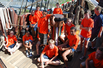 Students in orange crew shirts crowd around the capstan.