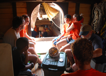 The foc's'le is packed with students and senior crew sheltering from the sun.