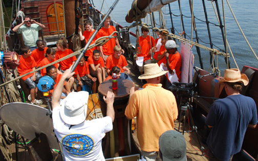 Captain Reynolds and the video crew set up a shot of the orange-clad student crew in front of the main mast.