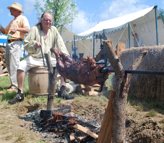 Woody Woodworth turns a roast pig on a spit.