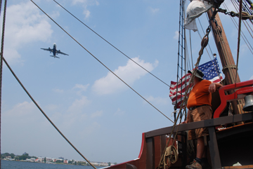 An airplane flies low over the ship.